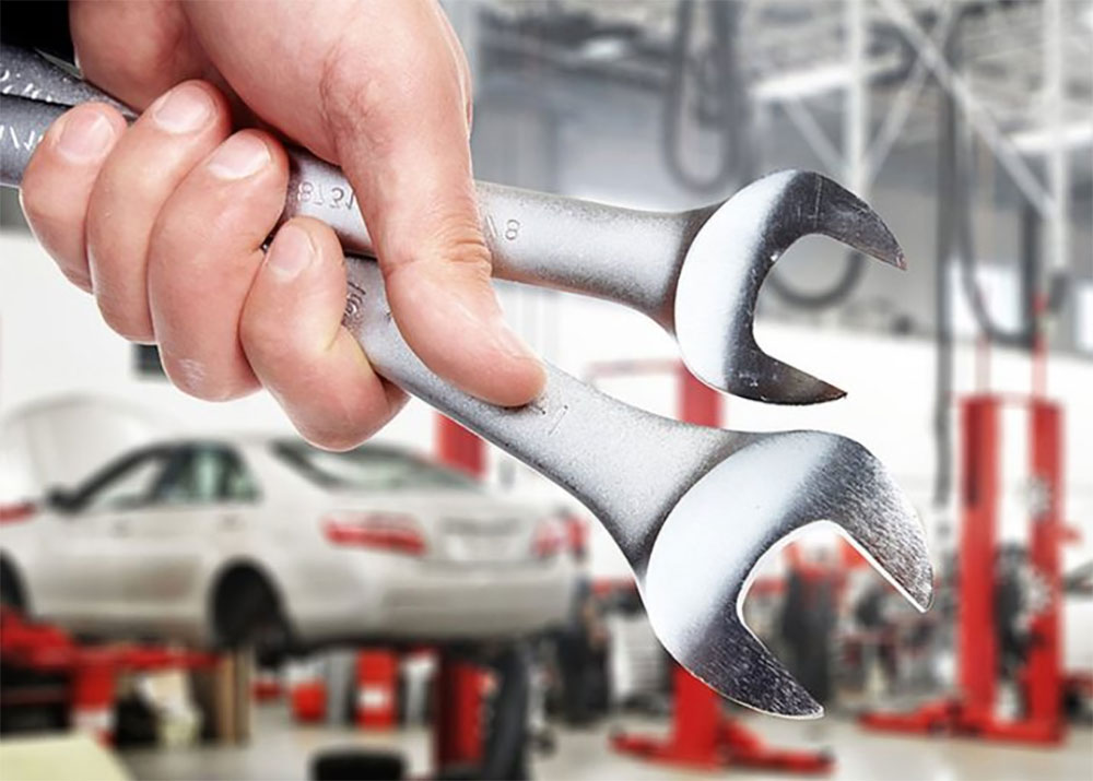 Spanners held in front of a workshop with cars raised on ramps